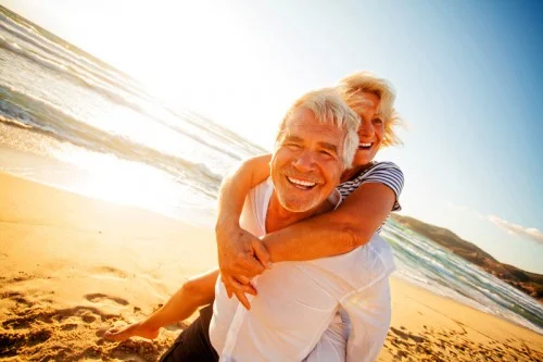 elderly couple smiling beach web