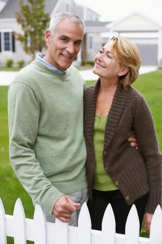 happy couple standing by white fence web